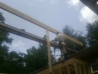 Carpenter setting a ridge beam over a new addition frame — Ice Dam Removal by Roofing Brothers in Kingston