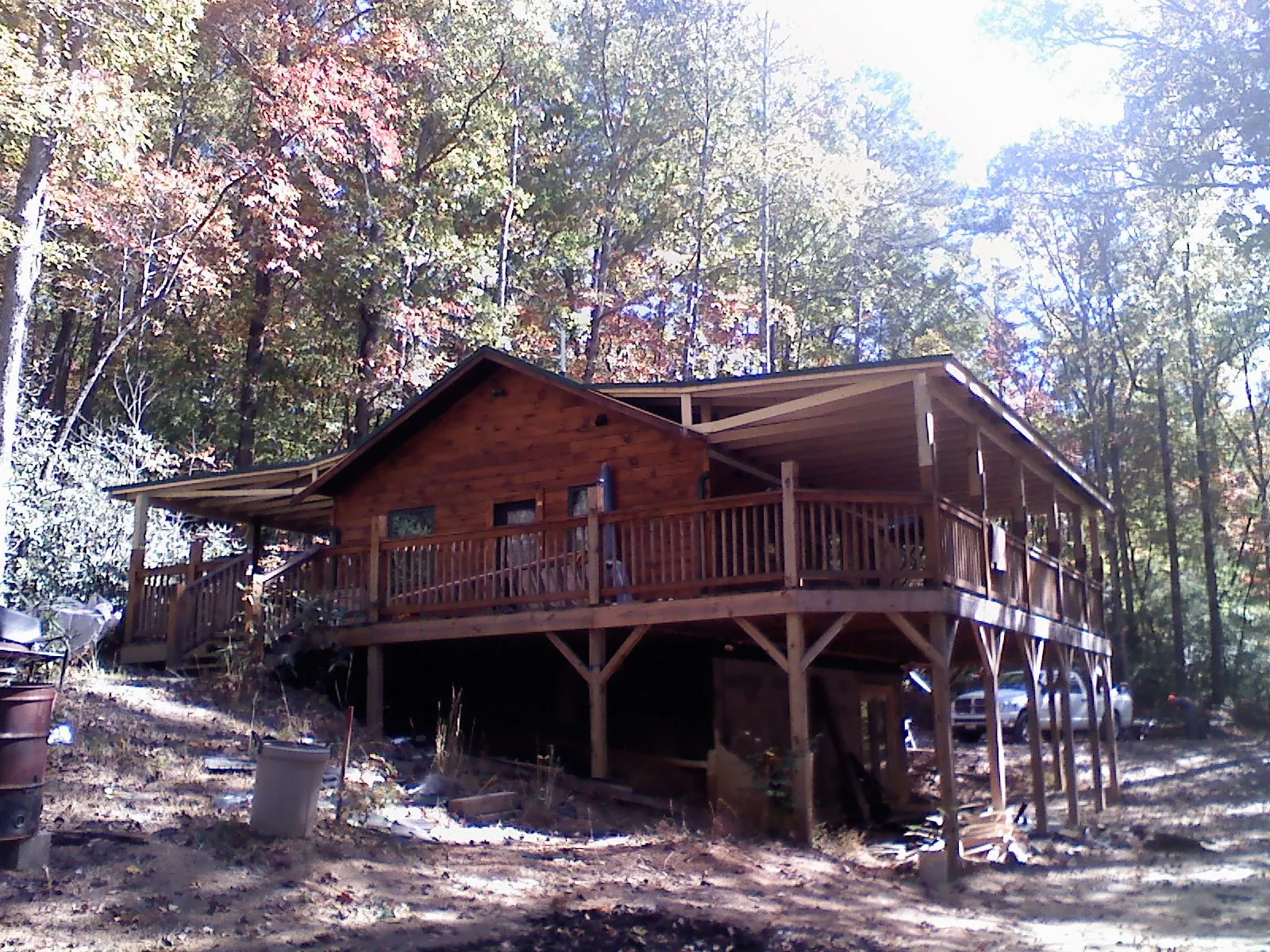 Log cabin with a wraparound porch and metal roof in the fall in Kingston
